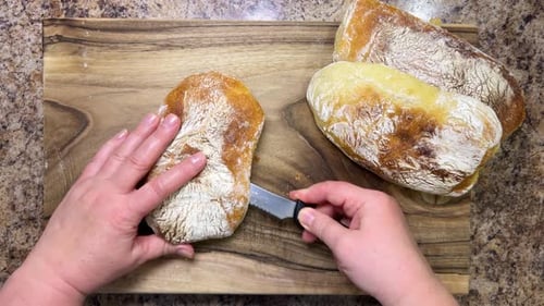 Ciabatta Bread Being Cut on Wooden Board