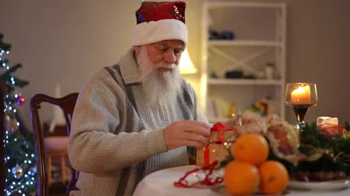Elderly Man Unwrapping Christmas Gift Indoors