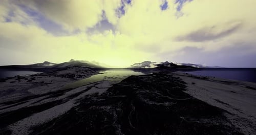 Dramatic Sunset Over Rocky Coastline and Tranquil Waters Near Mountains