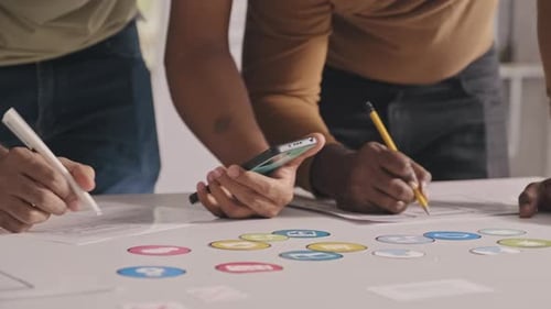 Mobile App Developers Working with Sketches and Smartphone