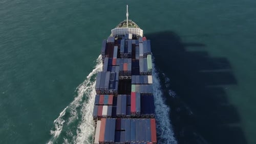 Aerial top view of a loaded container cargo vessel traveling over ocean.