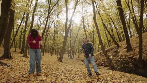 A Couple in Love is Having Fun Throwing Yellow Leaves on a Walk in the Park