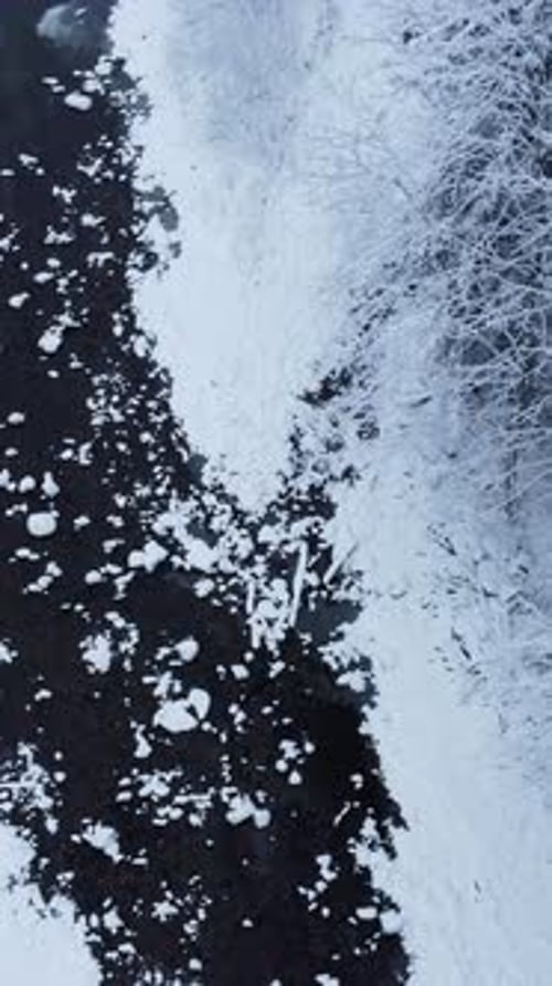 This is an Aerial View Showcasing an Icecovered River That Has Dark Water Beneath It