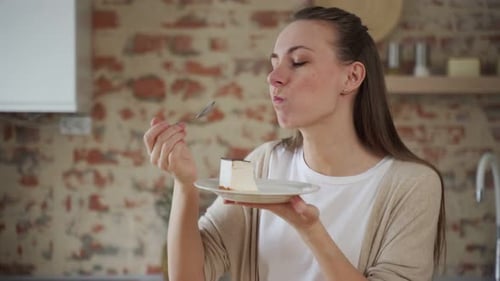 Young Woman Eating Delicious Slice of Cake at Home
