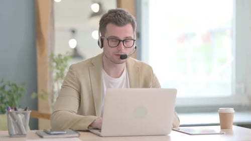Young Businessman with Headset Looking toward Camera in Call Center