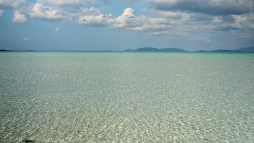 Beautiful landscape of calm turquoise sea water and mountains on the horizon at sunny day.