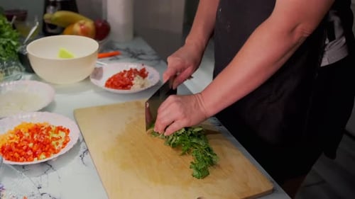 Close-up of hands chopping fresh cilantro on a wooden cutting board in a home kitchen