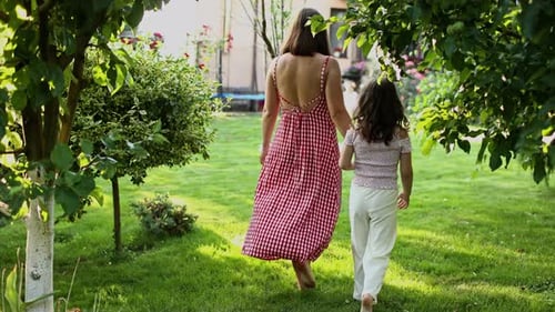 Woman and Child Walking Hand-in-Hand on Lawn