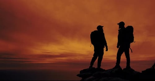 Men, sunset and silhouette on mountain for freedom, support and teamwork in dark