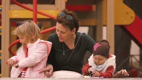 junge Mutter im Park mit ihren Kindern nimmt ihrer Tochter etwas aus der Tasche