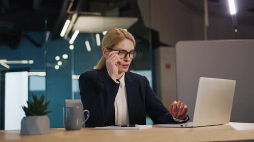 Woman Working At Desk Takes Off Glasses, Rubs Eyes