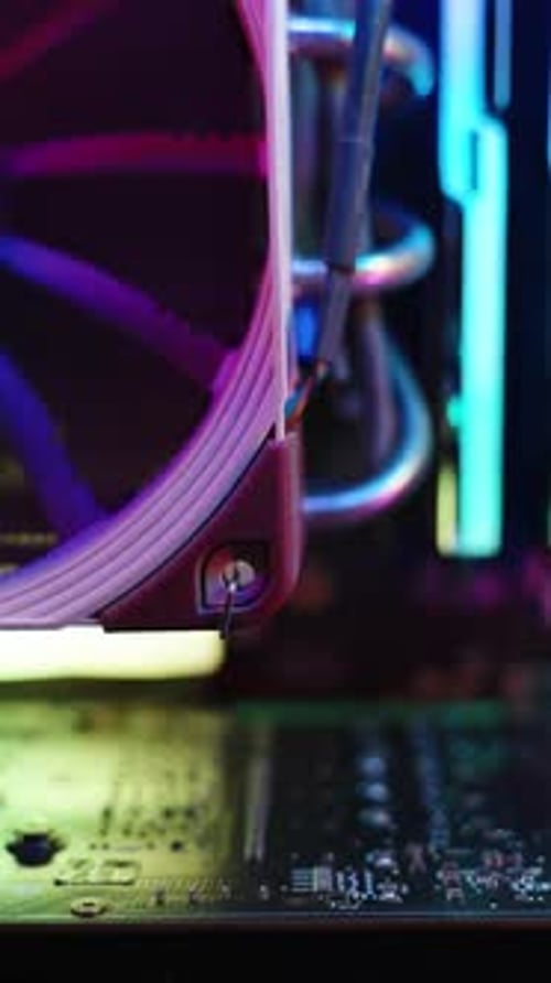 Vídeo vertical. Placa base de una computadora para juegos con iluminación RGB arcoíris en componentes electrónicos