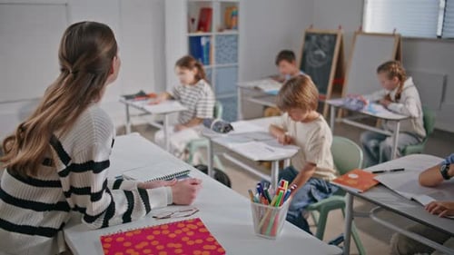 Teacher Supervising Elementary Students Working at Desks