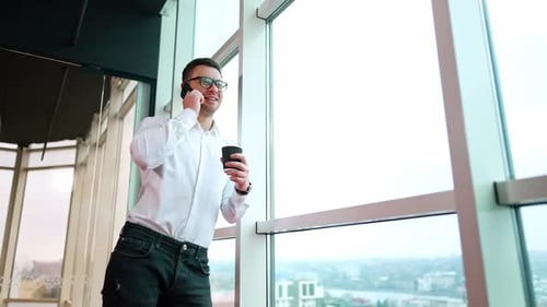 Relaxed smiling Caucasian male leaning on the window in office.