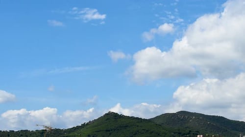 Timelapse of moving clouds over a mountain at midday. Cumulus.