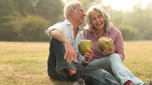 Senior Couple Enjoying Coconut Water in A Sunny Park During Afternoon