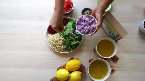 Adding onions Making a salad to dish beets quinoa seeds lemons and onions in the scene tomatoes and