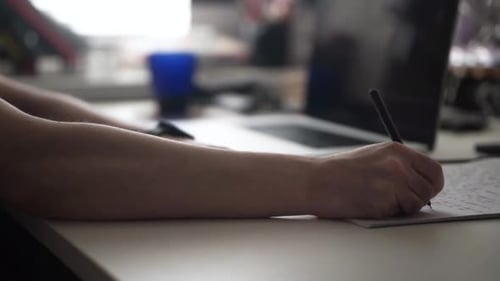 Man Writing Ideas While Working on Laptop