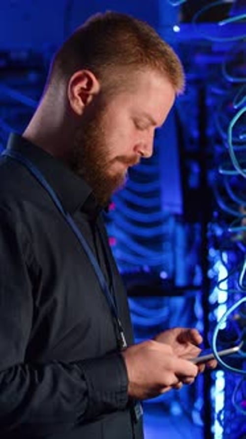 Man Checks Phone in Lit Server Room