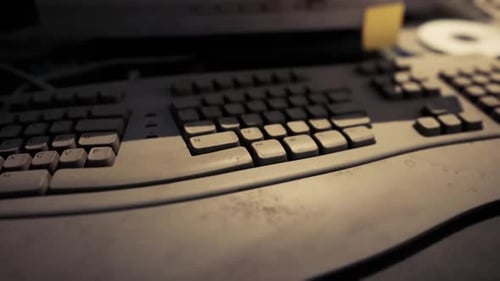 Dusty Keyboard on a Cluttered Desk with Warm Lighting at Nighttime