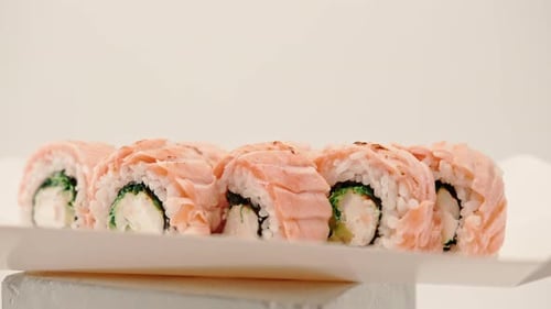 close-up of a roll with baked salmon, cucumber and cheese on a white background in a sushi delivery