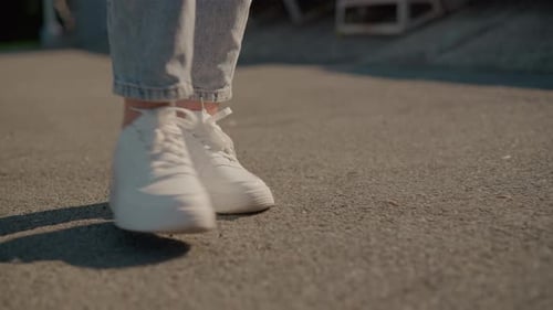 CloseUp of Legs Walking in White Sneakers on Sunlit Tarred Road