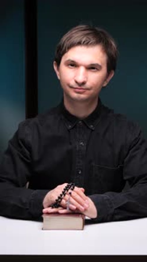 Young Man Sitting With Religious Book and Beads