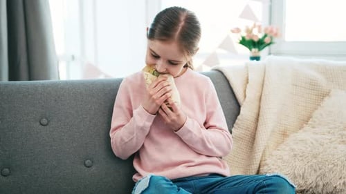 Girl Eats Wrap While Sitting on Couch