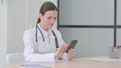 Young Doctor Browsing Smartphone in Clinic