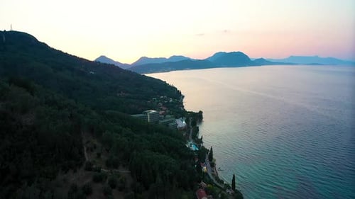 Sunset on the Greek coast. The sea, mountains in the background, some buildings can be seen.