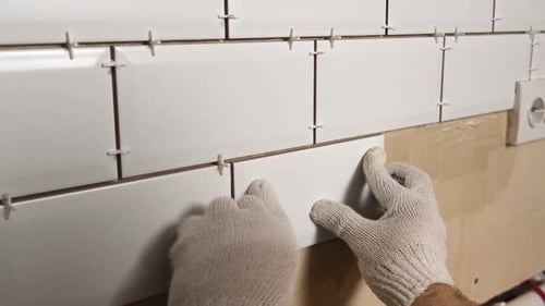 Gloved Hands Tiling White Rectangular Tiles on Wall