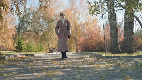 Woman Walking Through Park in Autumn Coat
