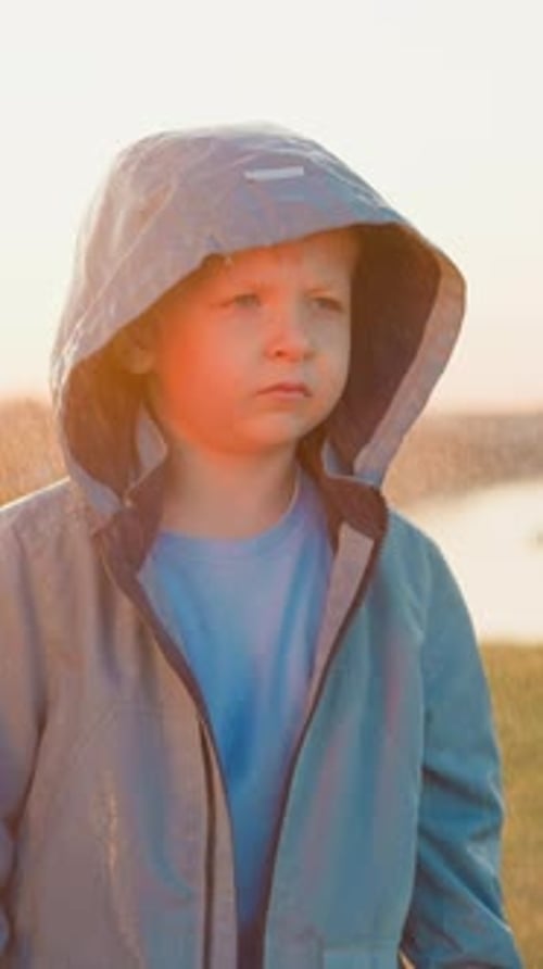 Young Child in Blue Jacket Stands in Field