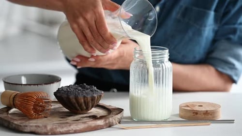 Woman Pouring Milk into a Jar for Drink
