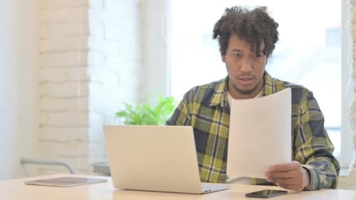 Young Adult Working with Laptop and Paper