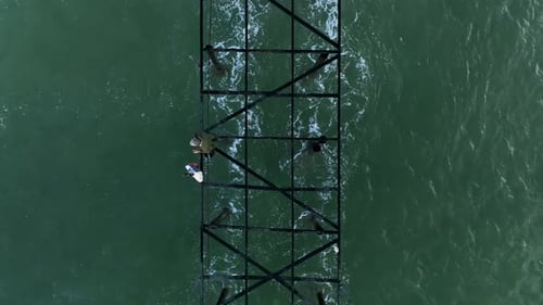Der Fischer fängt Fische vom Pier aus Der Sturm auf dem Meer hat eine wunderschöne Farbe