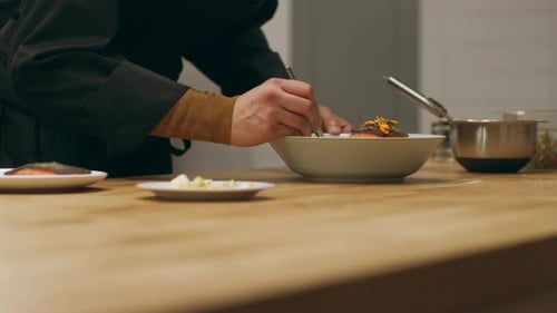 Chef plating salmon with edible flower garnish
