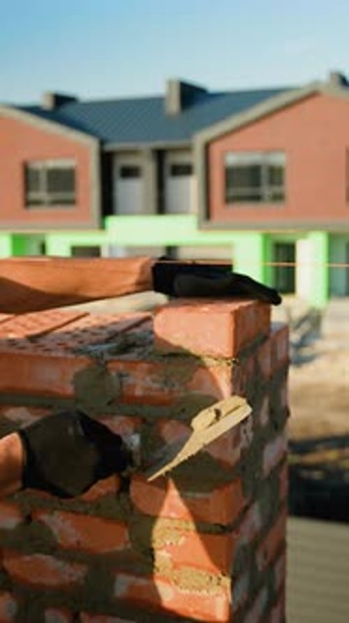 Builder Laying Bricks at Townhouse Construction Site