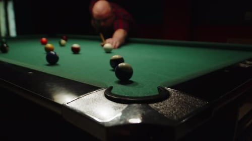 Mann spielt eine Sportpartie Billard, schlägt Ball mit Queue und zielt auf die Tasche, Vorderansicht des kaukasischen Mannes