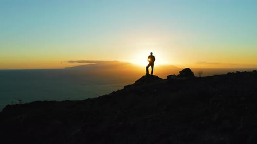 Silhouette of Hiker Man Standing on Mountain Top at Sunset
