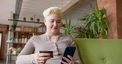 Woman Using Phone and Credit Card on Couch