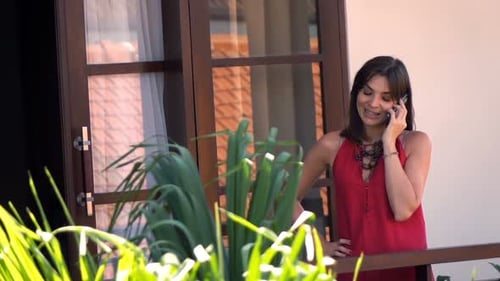 Young caucasian woman chatting happily on cellphone on terrace in countryside
