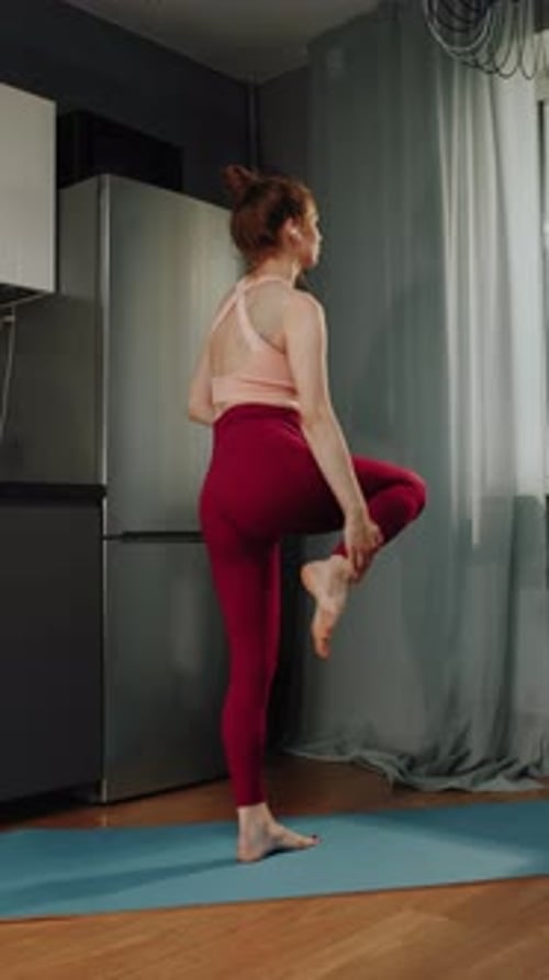 Woman Stretching Legs on Yoga Mat in Kitchen