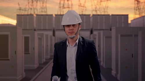 Vorderansicht eines asiatischen Geschäftsmannes, der einen Bauplan in der Hand hält, während er mit elektrischer Energie geht