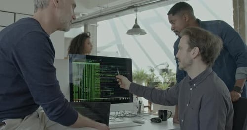 Três engenheiros do sexo masculino examinando o Código em um monitor de computador no escritório