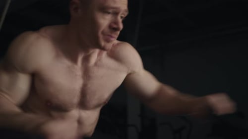 Muscular Man Exercising on Elliptical in Gym