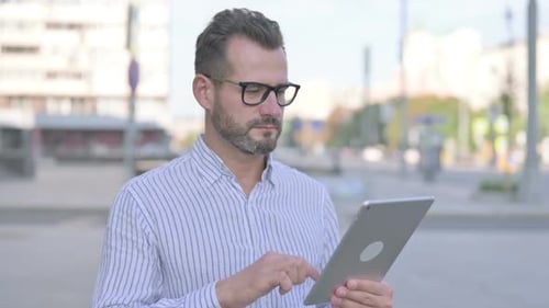 Man Using Tablet Device Outdoors in the City