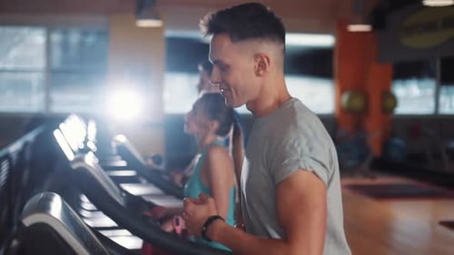 Glücklicher junger Mann nutzt Smartwatch auf einem Laufband Fitnessstudio Sport Technologie Fit Lifestyle Männliches Training