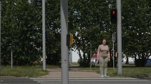 Mulher se aproxima da passagem para pedestres e toca no botão de toque