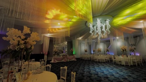 Wide shot luxurious elegant restaurant interior, colored party lights, big chandelier